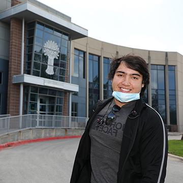 赌钱app可以微信提现 honors student wearing a face mask posing in front of Harvesters food bank